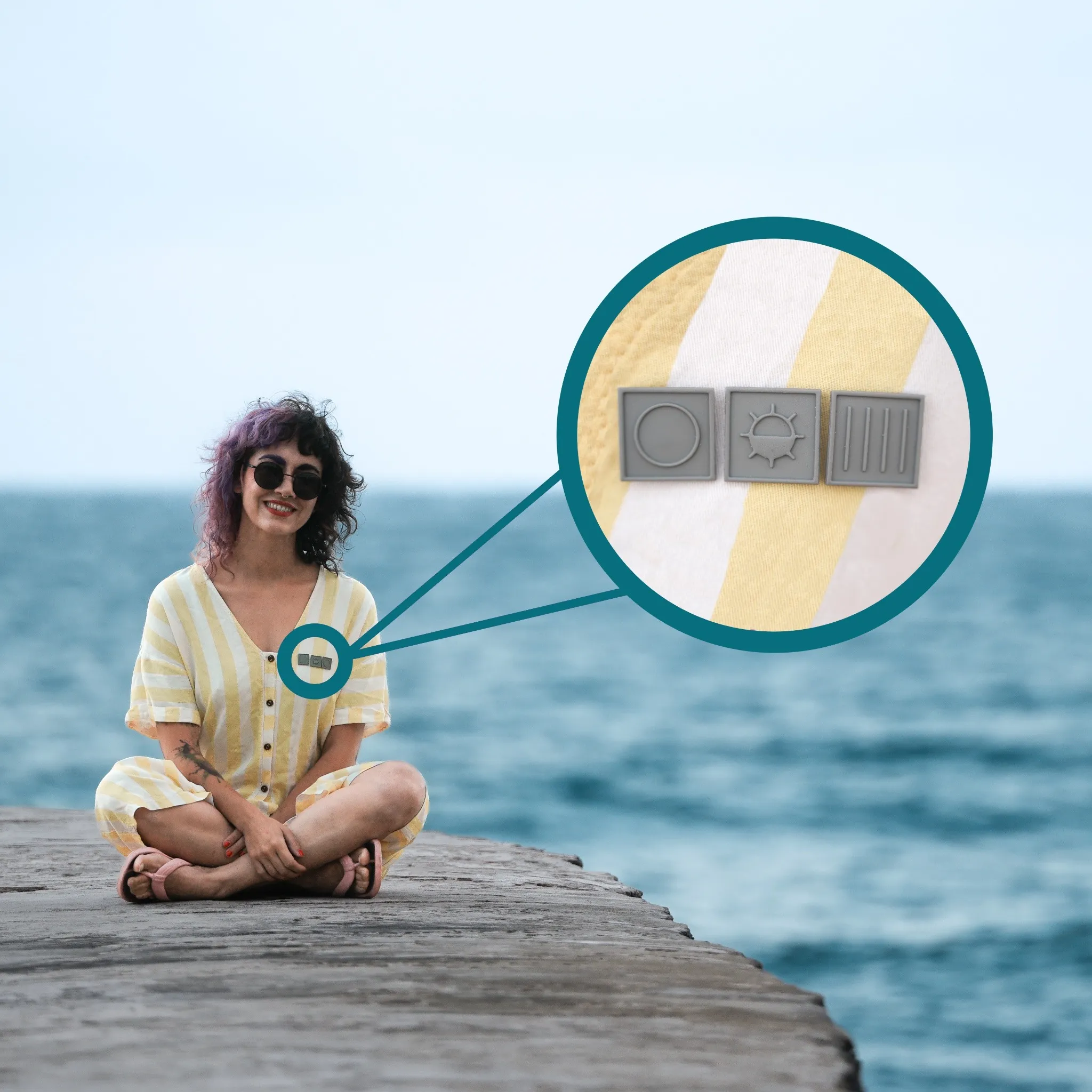 Mujer sentada junto al mar con vestido de rayas amarillas, mostrando símbolos táctiles de círculo, sol y barras verticales.